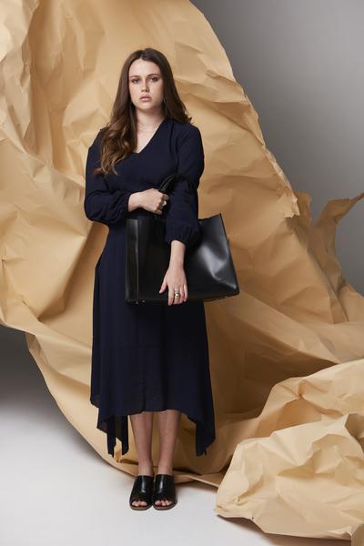 Woman standing with Harlequin Belle Downtown large leather women's bucket bag black